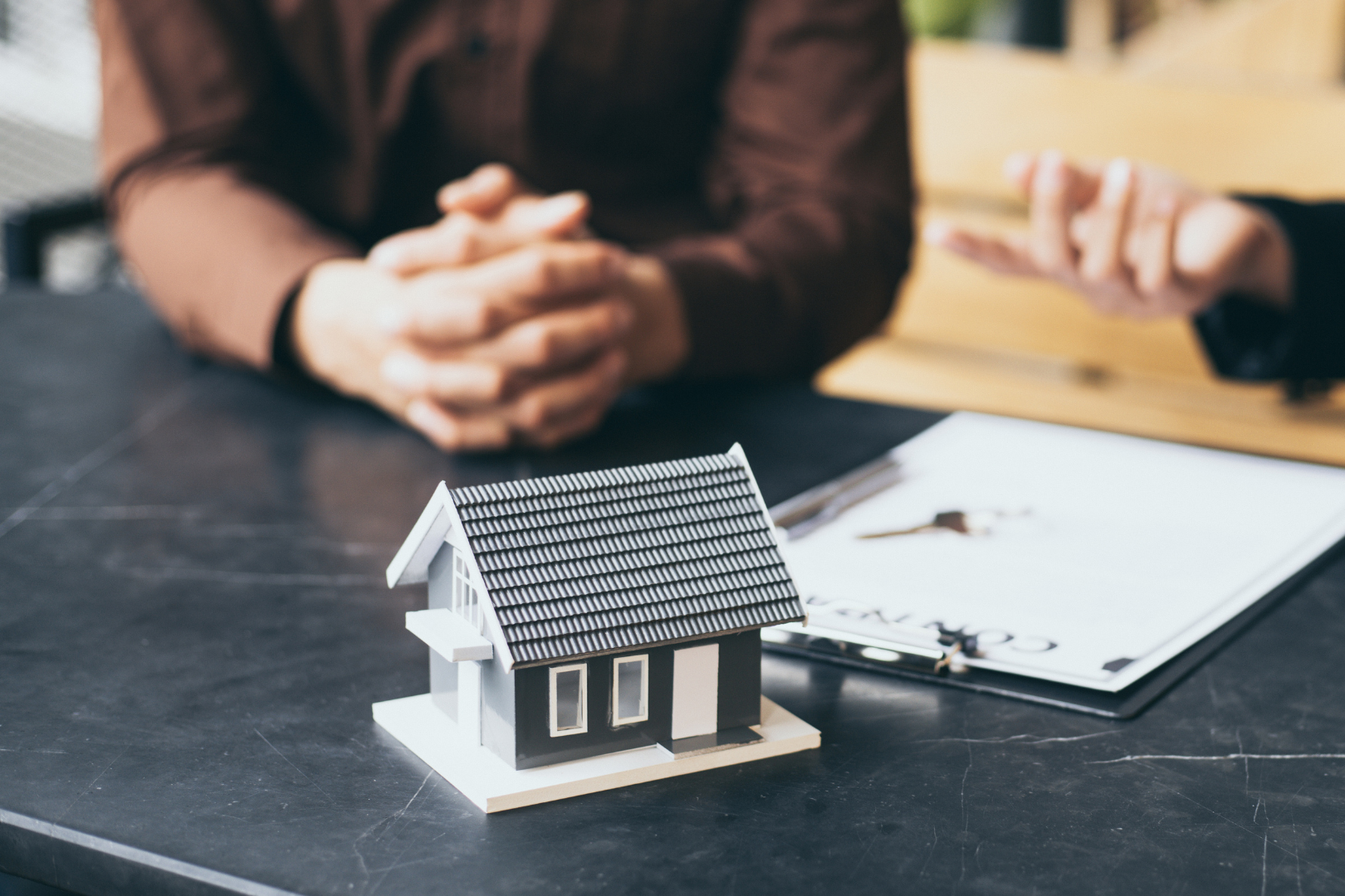 Conveyancing and property law advice – house model and contract discussion, symbolising property services from Martin Shepherd Solicitors in Hertfordshire and North London.