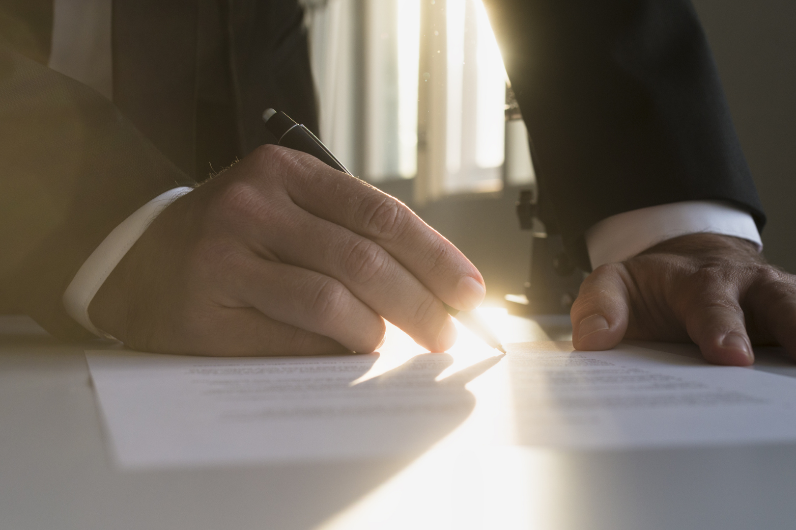 Signing a legal document in warm sunlight representing the hero background for the About Us page by Martin Shepherd Solicitors in North London, Hertfordshire, Potters Bar, and surrounding areas.