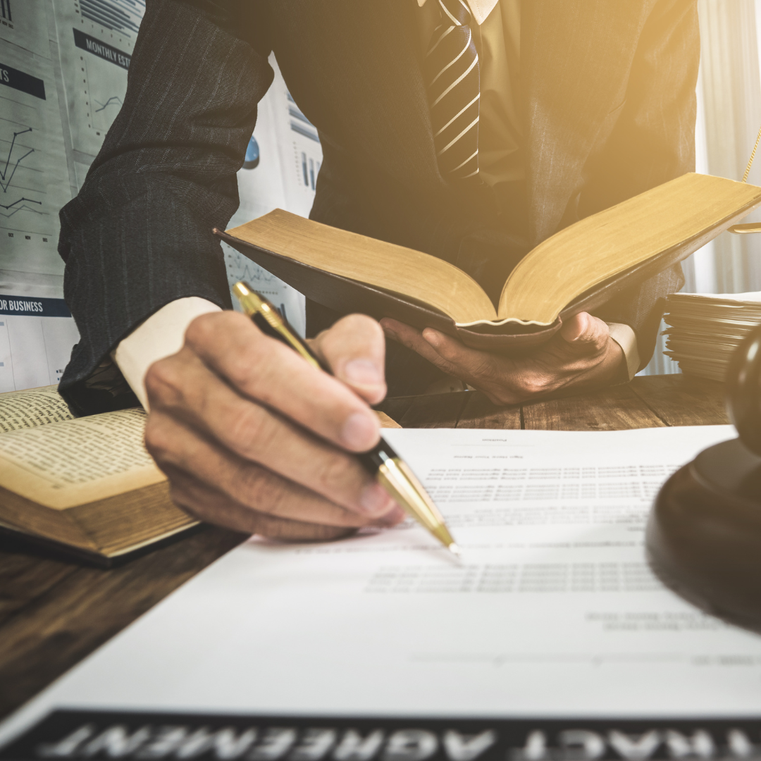 Solicitor reviewing legal books and signing documents representing commercial agency dispute services by Martin Shepherd Solicitors in Potters Bar, Hertford and North Finchley.