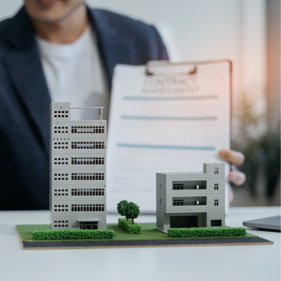 Business professional presenting property models and a contract representing the guidance offered by Martin Shepherd Solicitors for acquiring commercial property in North London and Hertfordshire