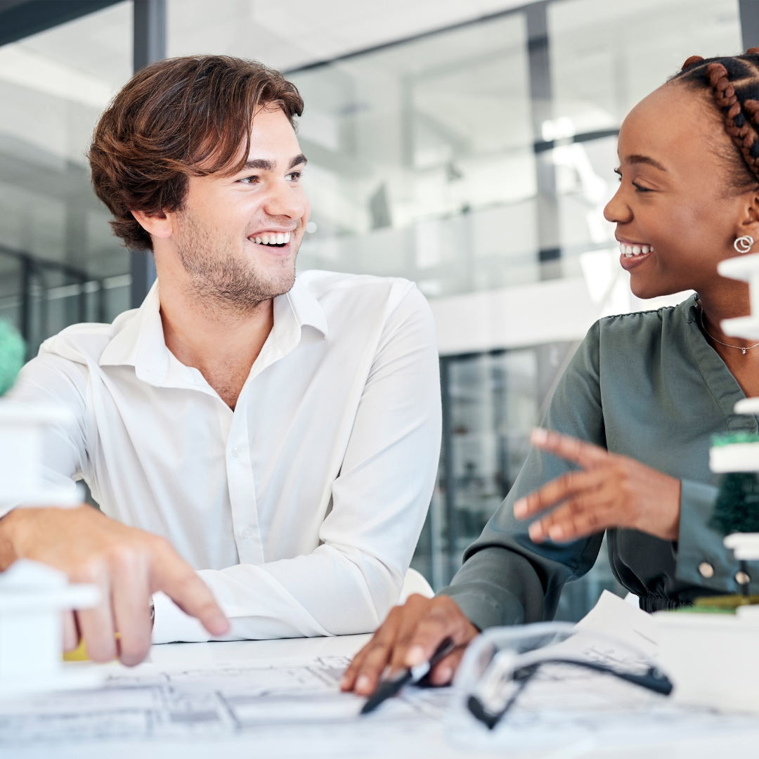 Two colleagues discussing architectural plans in a modern office, representing legal guidance for development and planning agreements by Martin Shepherd Solicitors in Potters Bar, Hertford and North Finchley, serving North London and Hertfordshire.